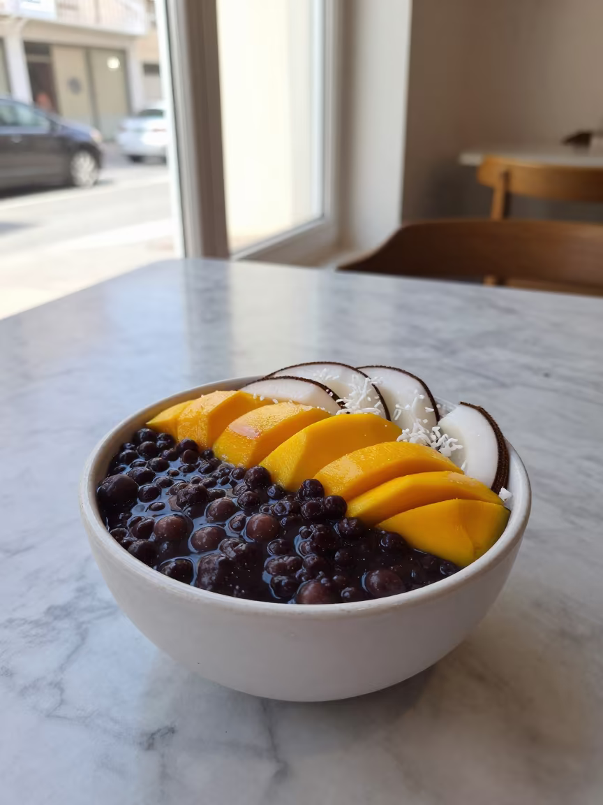 Acai Bowl with Mango and Coconut on Marble Table in on a marble cafe table in Misrata