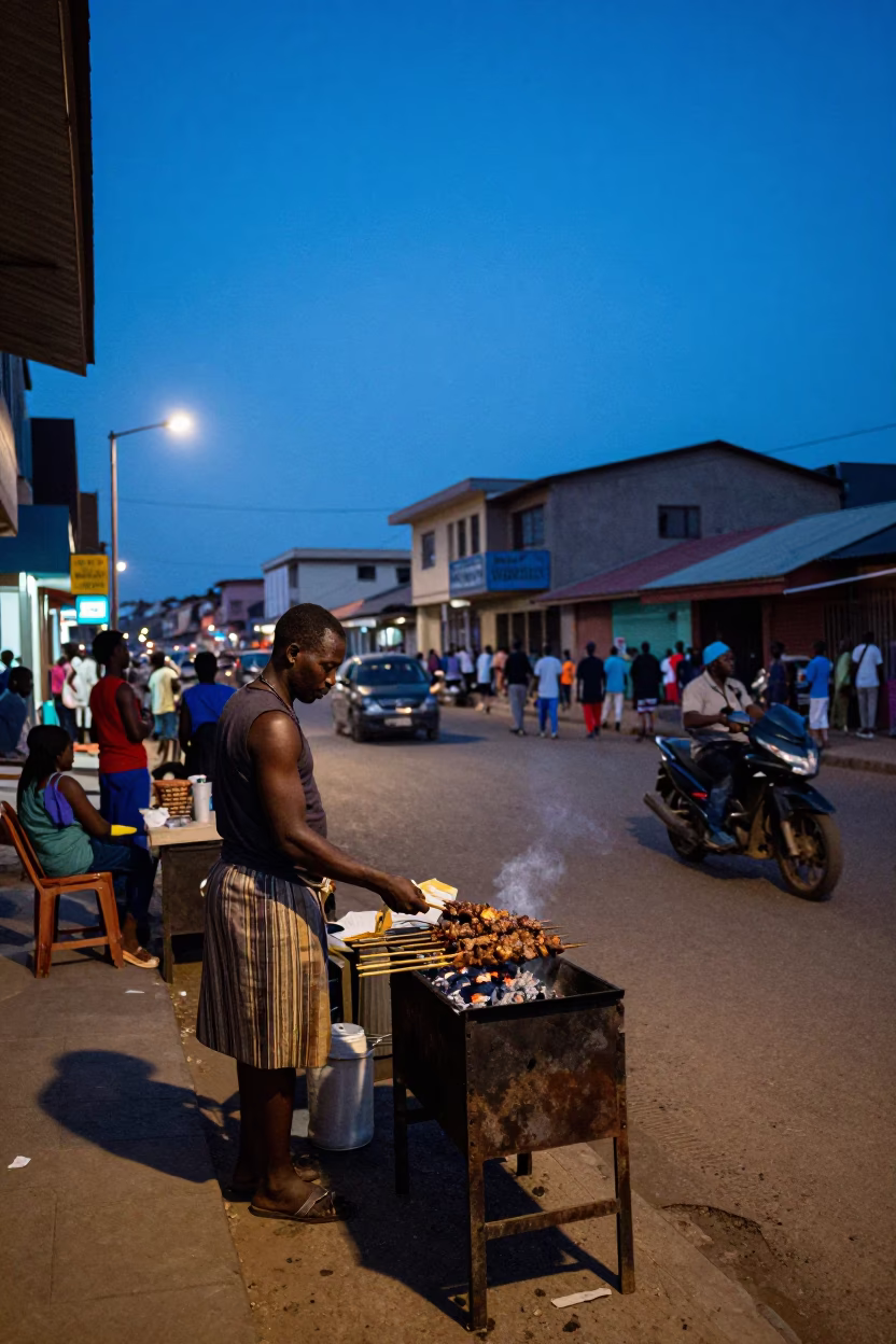 Accra Ghana Blue Hour Street Scene with Grilled Kebab Vendor and Lively Market Crowd in in Accra, Ghana