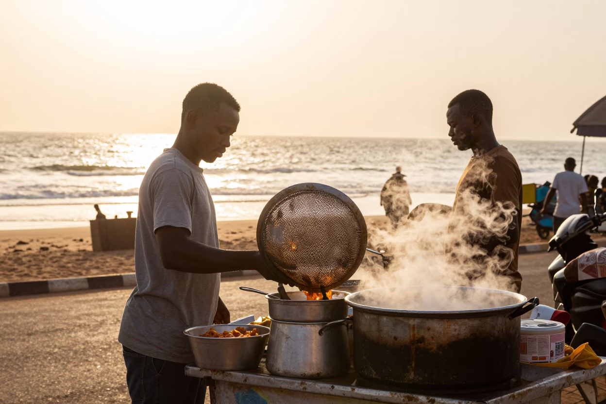 Accra Ghana street vendor selling breakfast near lagoon at sunrise with metal colander in in Accra, Ghana