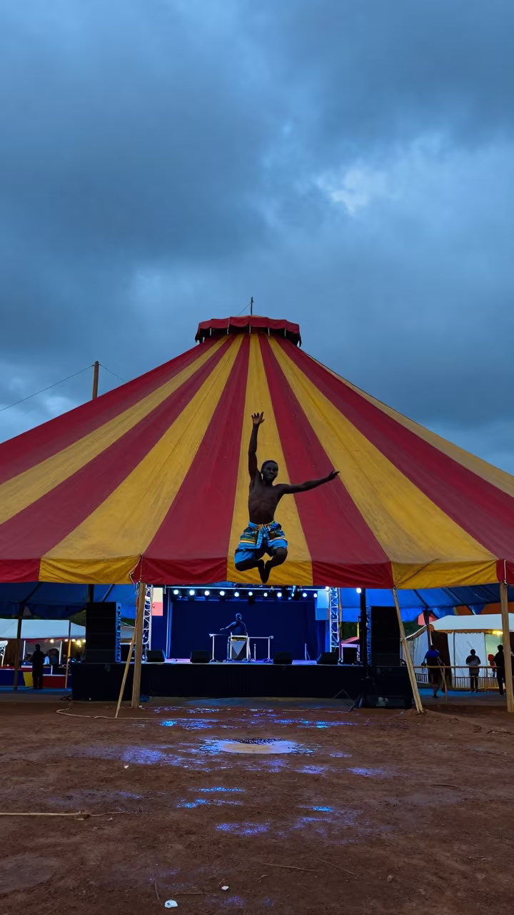 Acrobat Mid-Air Under Striped Tent at Mbanza Kongo Festival in on a festival main stage in M'banza-Kongo