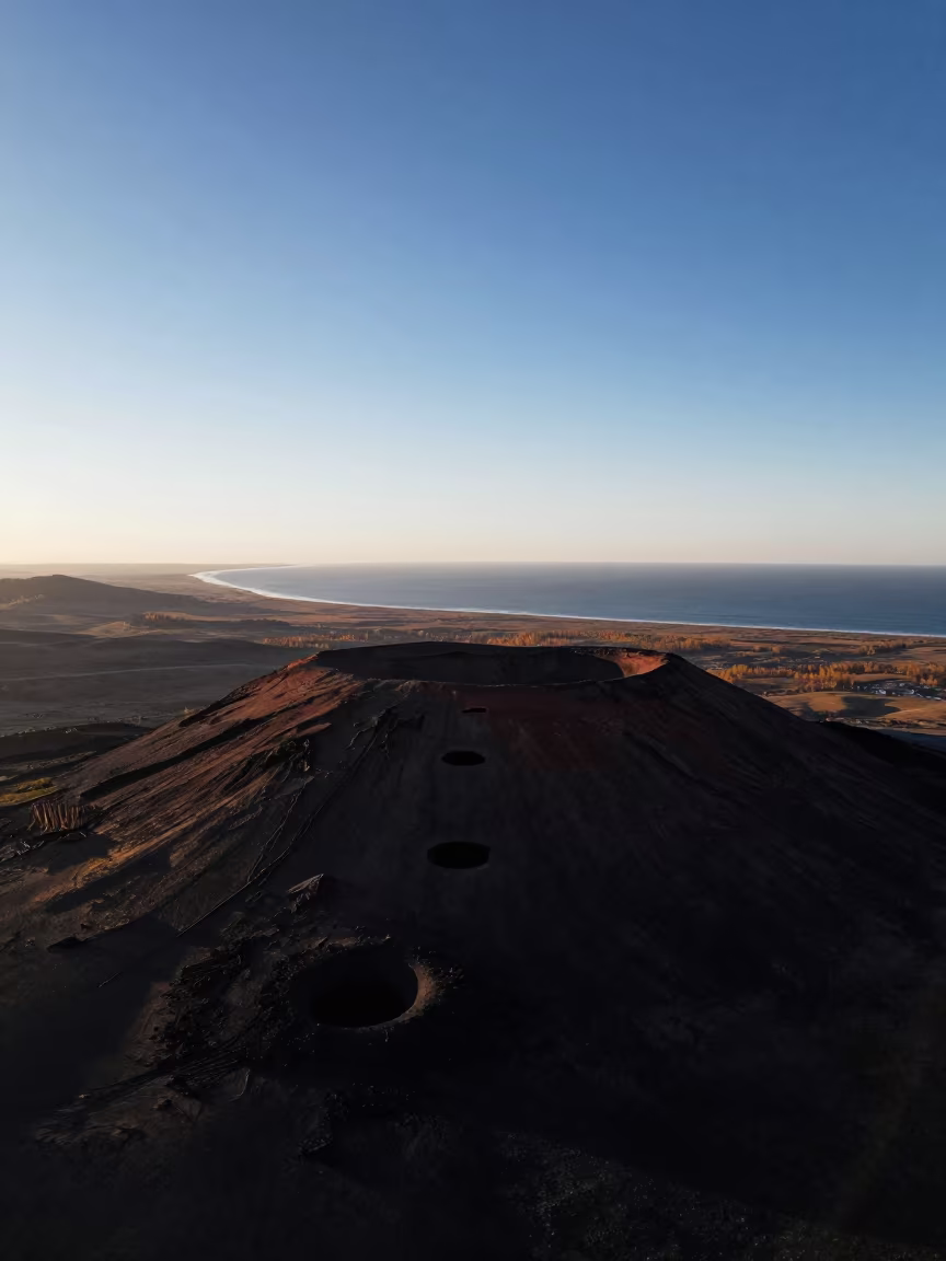 Aerial Crater Chain on Tibetan Plateau at Dusk in far above surf-scalloped coastline in Tibet