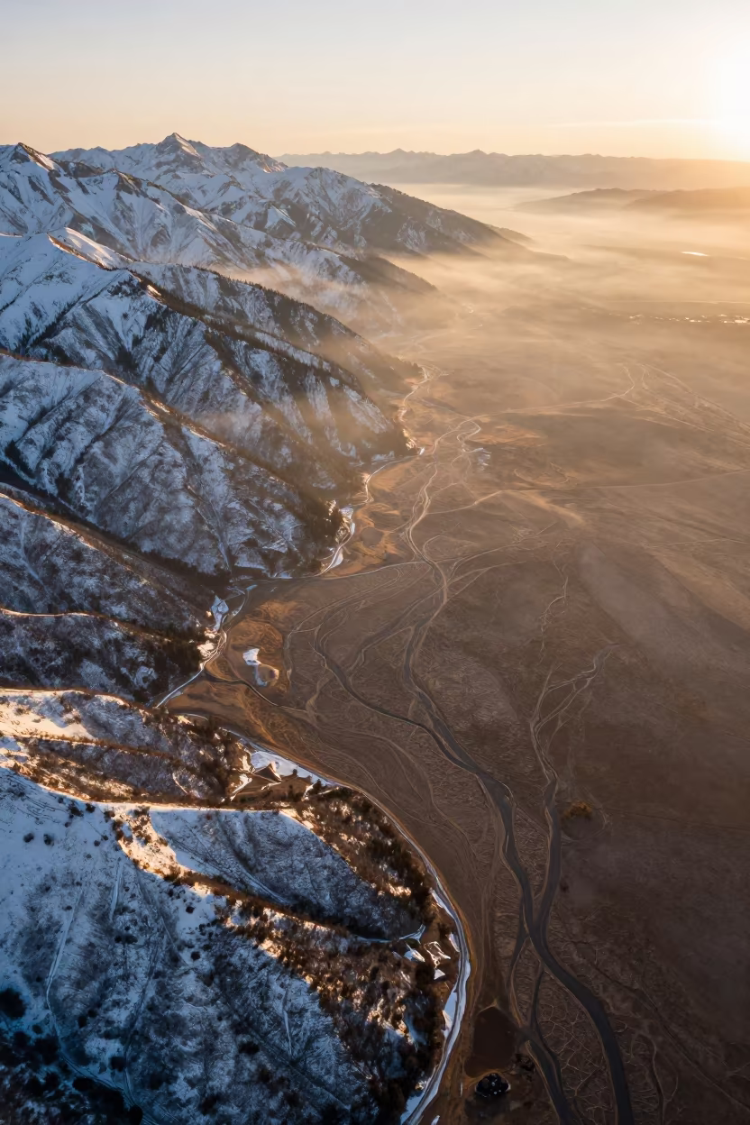 Aerial Golden Hour Over Snowy Canadian Mountains in above dune fields and dry wadis in Canada