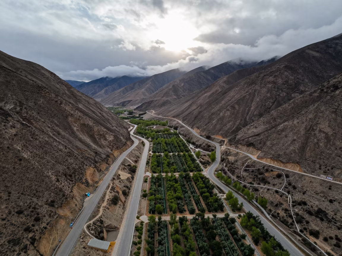 Aerial Mountain Switchback Road in Spring Dawn Light in far above orchard blocks and irrigation lines near Lhasa