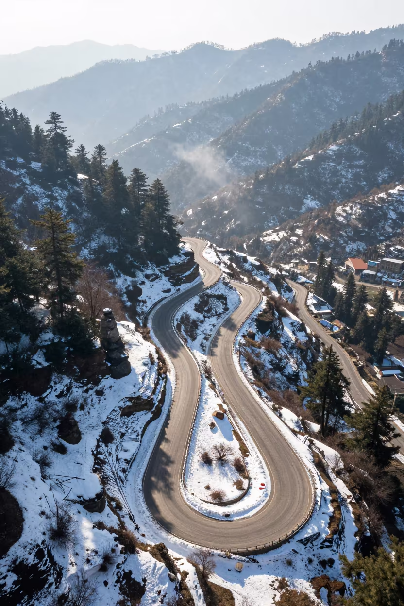 Aerial View of Snowy Mountain Pass Road Near Shimla in beside a summit cairn above the tree line near Shimla