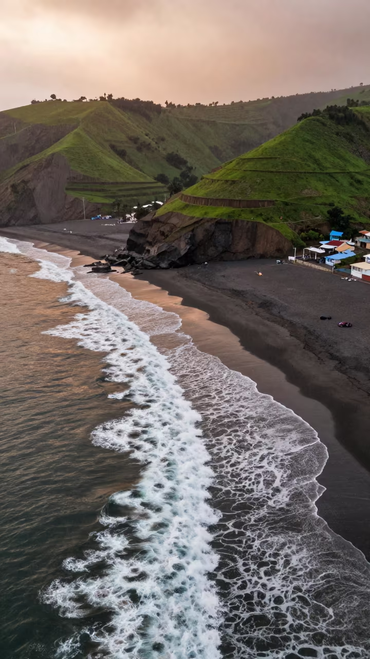 Aerial surf lines black sand coast wet season dusk in far above terraced hillsides near Lima