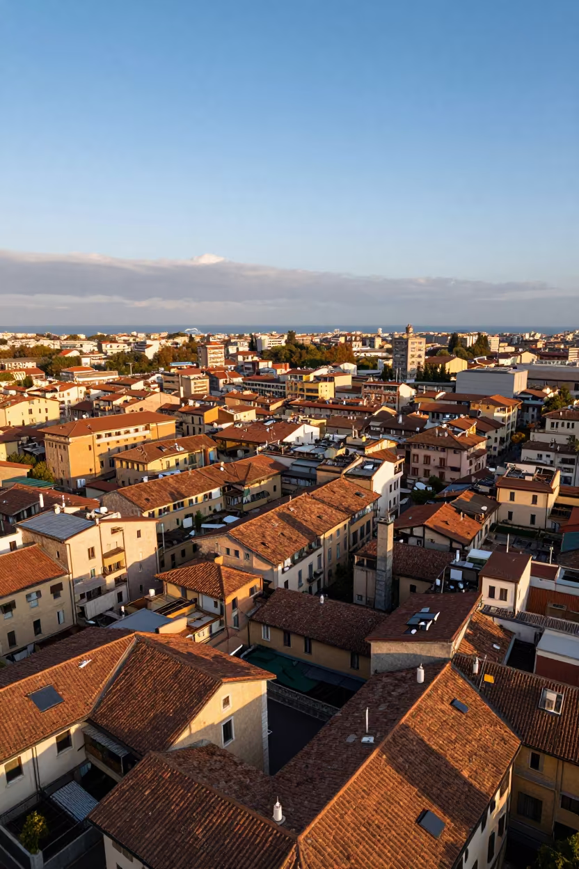 Aerial view of Milan rooftops in evening orange light in far above surf-scalloped coastline near Milan