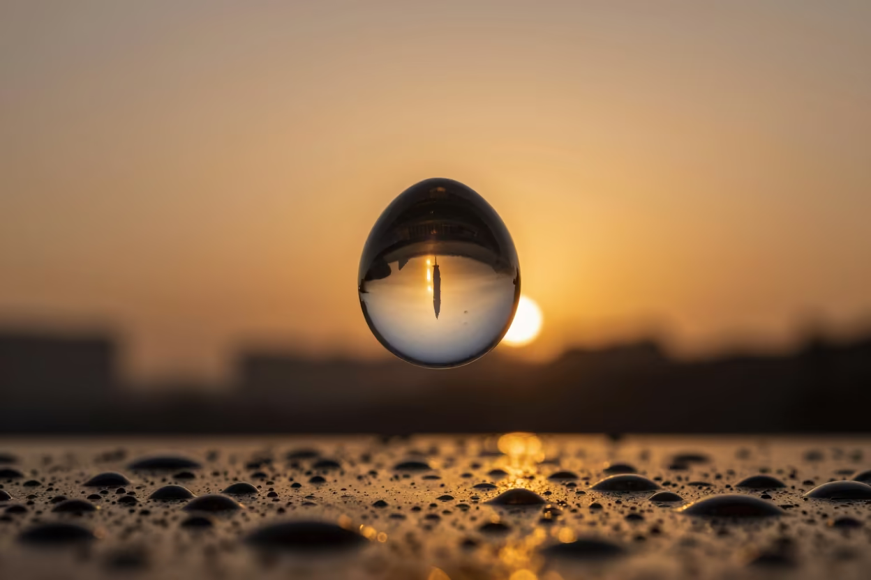 Amber Skyline Reflected in Water Droplet in across a rain-beaded metal surface near Guiglo