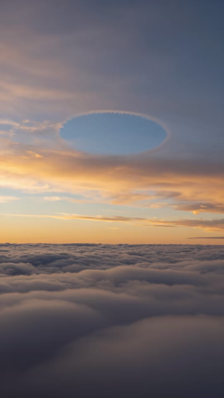 Amber Sunset Fallstreak Hole Over Australian Sky in beneath fast-moving cloud bands in Australia