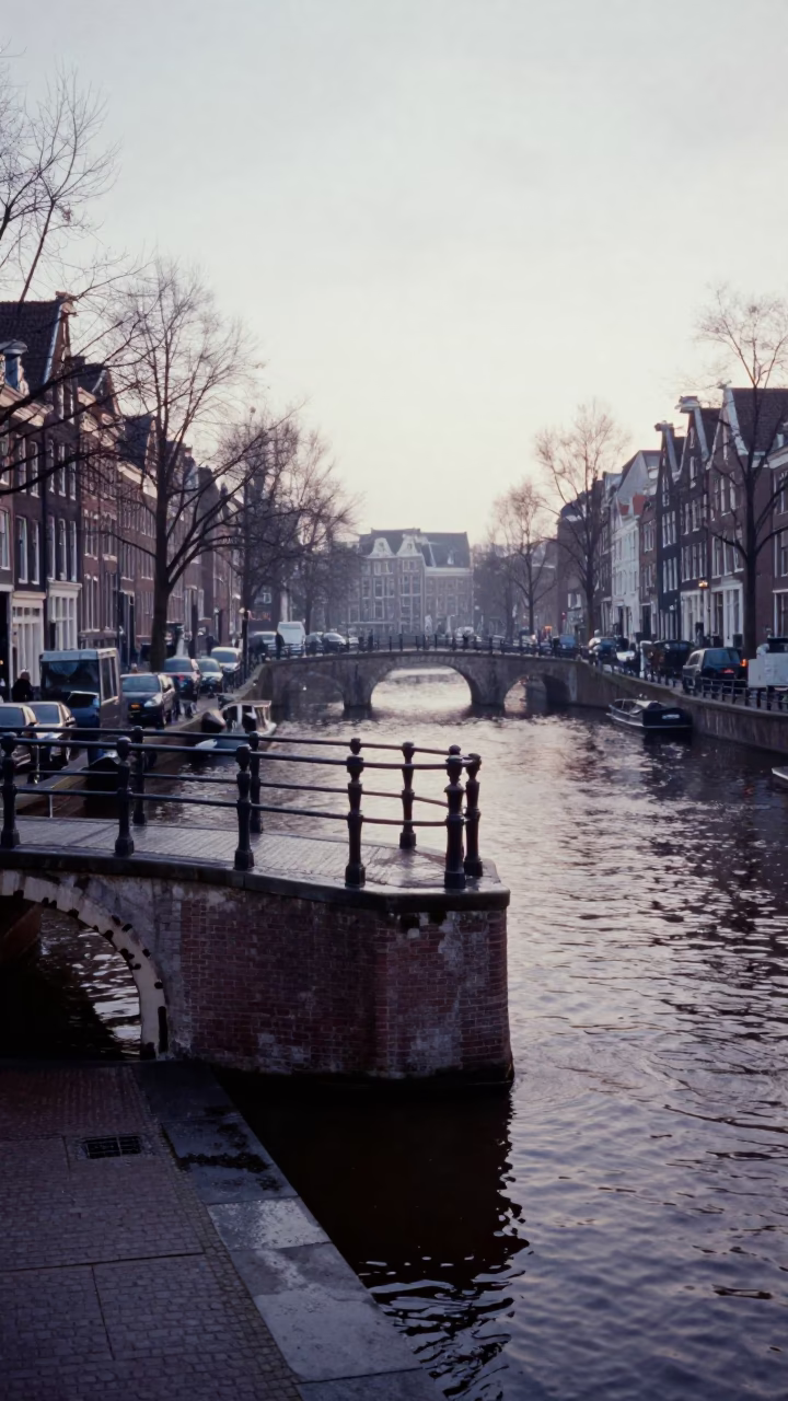 Amsterdam Canal at Dawn with Bridge Pier and Damp Cobblestone Street in in Amsterdam, Netherlands