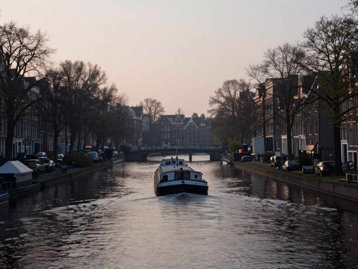 Amsterdam Canal Bend at Dawn with Navigating Barge and Tree Lined Banks in in Amsterdam, Netherlands