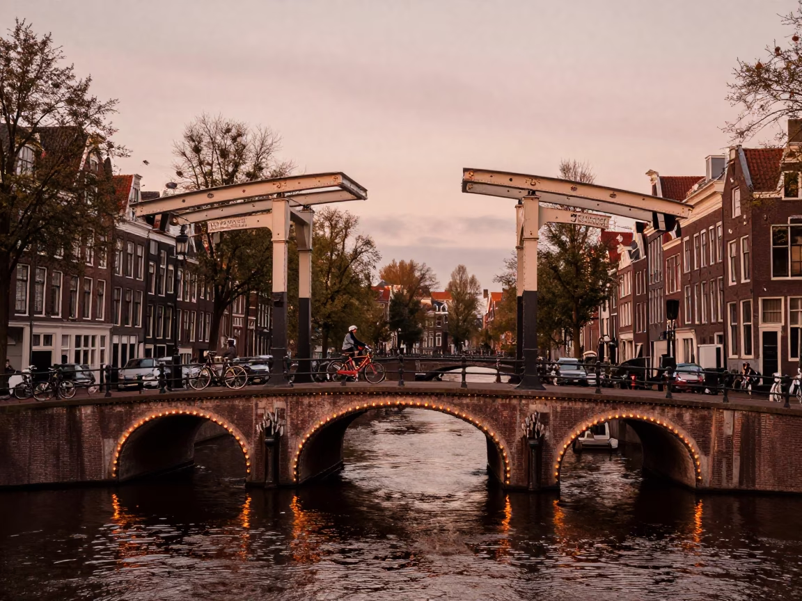 Amsterdam Canal Bridge at Dusk with Cyclists and Traditional Brick Architecture in in Amsterdam, Netherlands