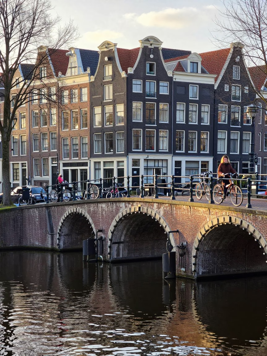 Amsterdam Canal Bridge Morning Scene with Cyclists and Coffee in in Amsterdam, Netherlands