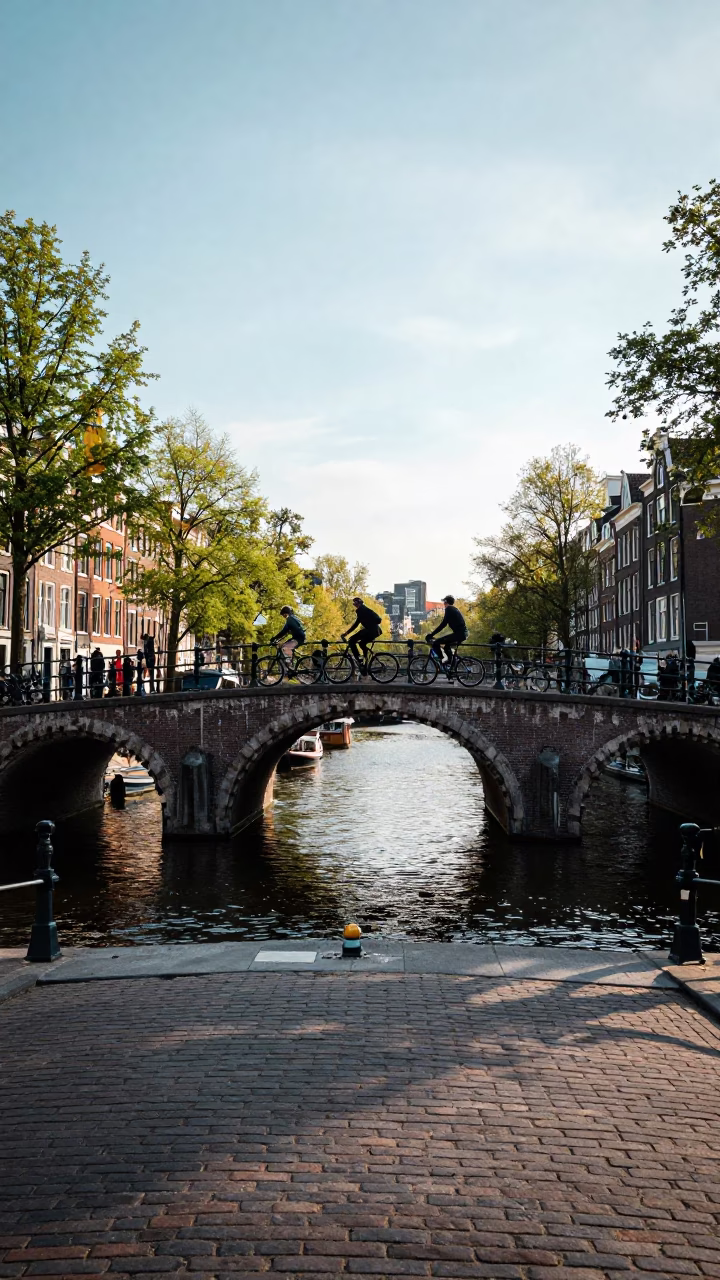 Amsterdam Canal Bridge Overpass with Cyclists and Boats in Late Afternoon Light in in Amsterdam, Netherlands