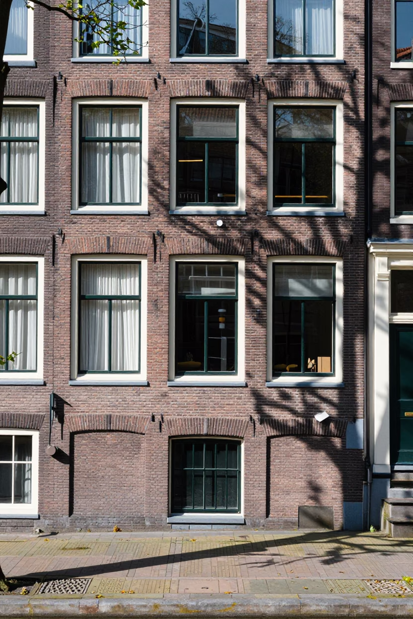 Amsterdam Canal House Facade with Paint Flecks and Leaf Shadows Under Noon Sun in in Amsterdam, Netherlands