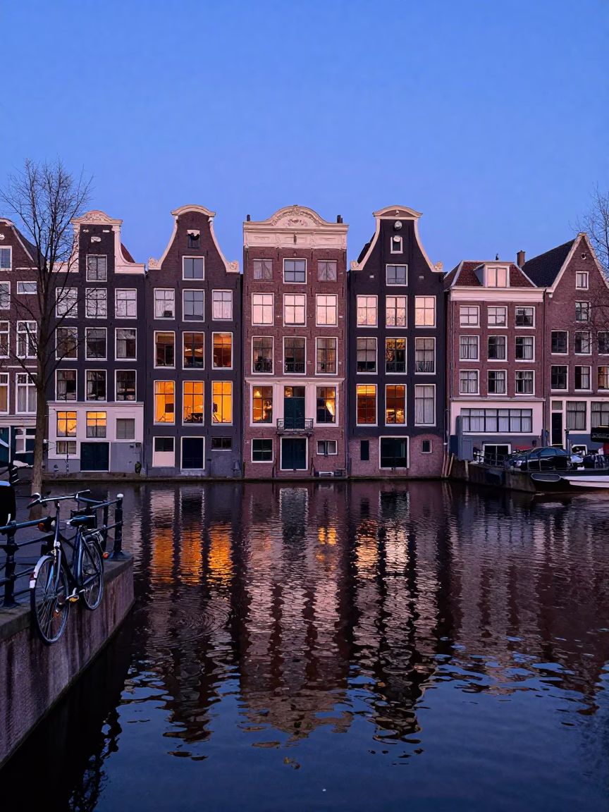 Amsterdam canal house reflection in indigo twilight with bicycle parked near brick facade in in Amsterdam, Netherlands