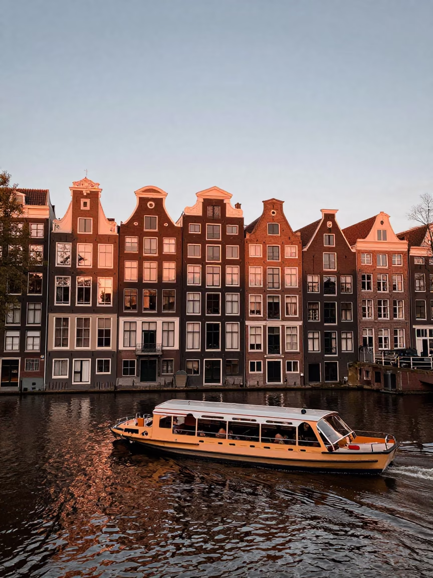 Amsterdam Canal Houseboats at Dusk with Water Taxi Navigating Narrow Waterways in in Amsterdam, Netherlands
