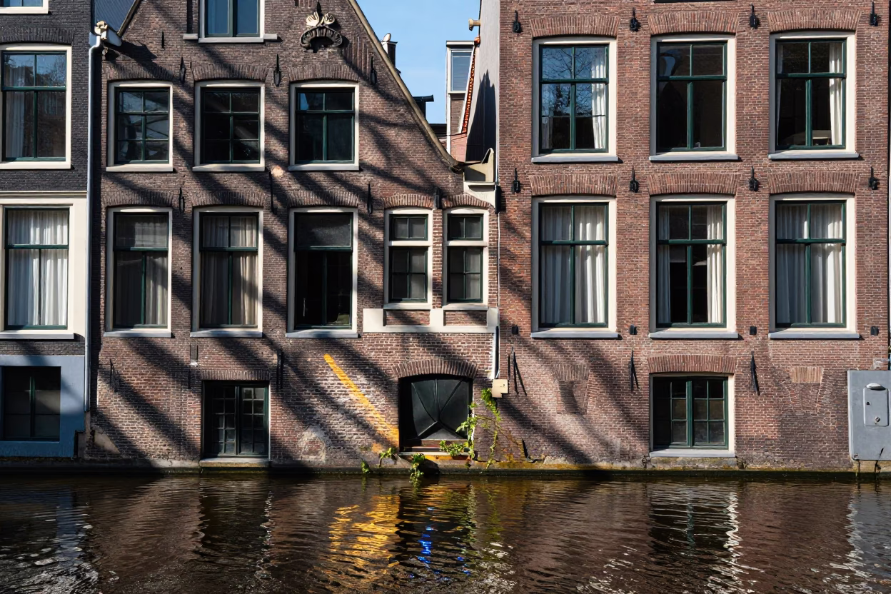 Amsterdam Canal Midday Sunlight Reflecting on Brick Houses and Traditional Dutch Architecture in in Amsterdam, Netherlands