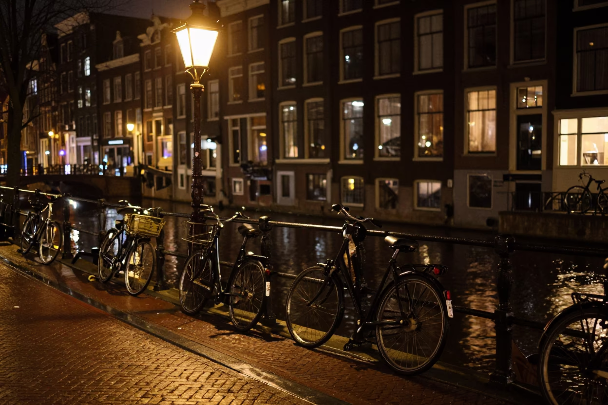 Amsterdam canal night street scene with parked bicycle and wet cobblestones in in Amsterdam, Netherlands