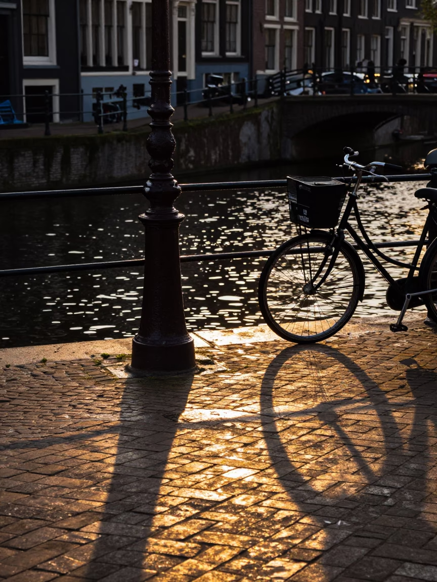 Amsterdam Canal Side Late Afternoon Light Reflecting on Cobblestones and Bicycle Wheels in in Amsterdam, Netherlands