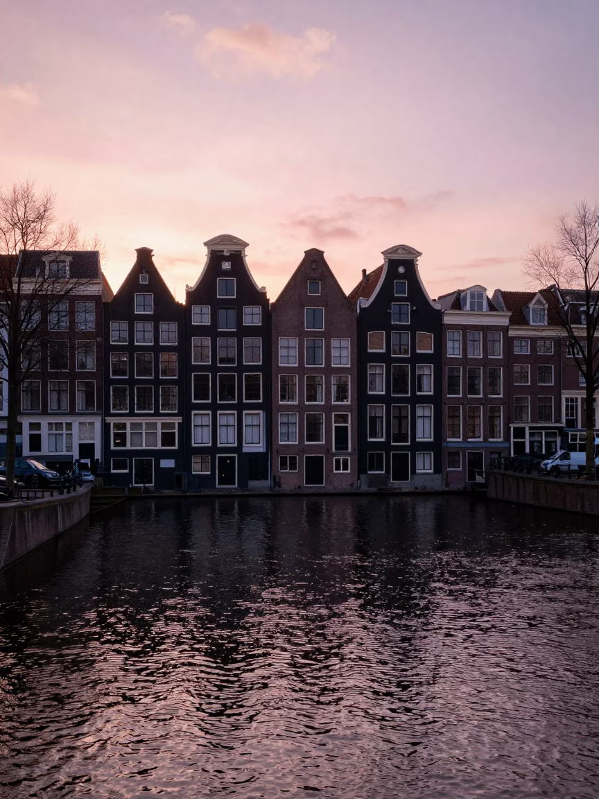 Amsterdam Canal Sunset View with Traditional House Facades and Reflecting Water in in Amsterdam, Netherlands