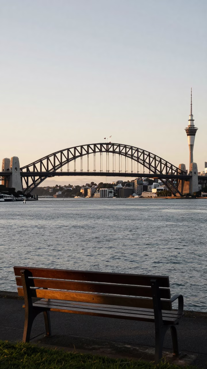 Auckland Harbour Bridge and Sky Tower at Nautical Dawn with Sunlight on Bench in in Auckland, New Zealand