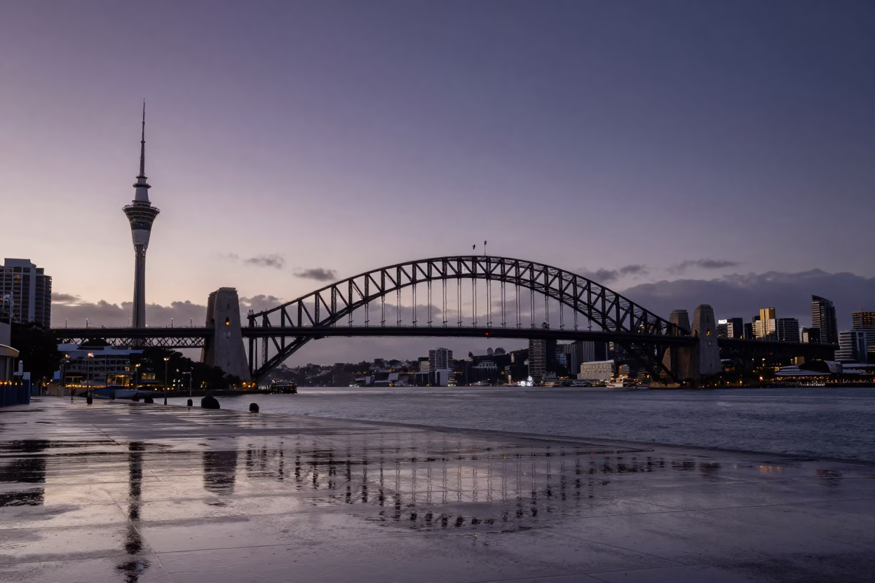 Auckland Harbour Bridge and Sky Tower reflected in wet street puddles at nautical dawn in in Auckland, New Zealand