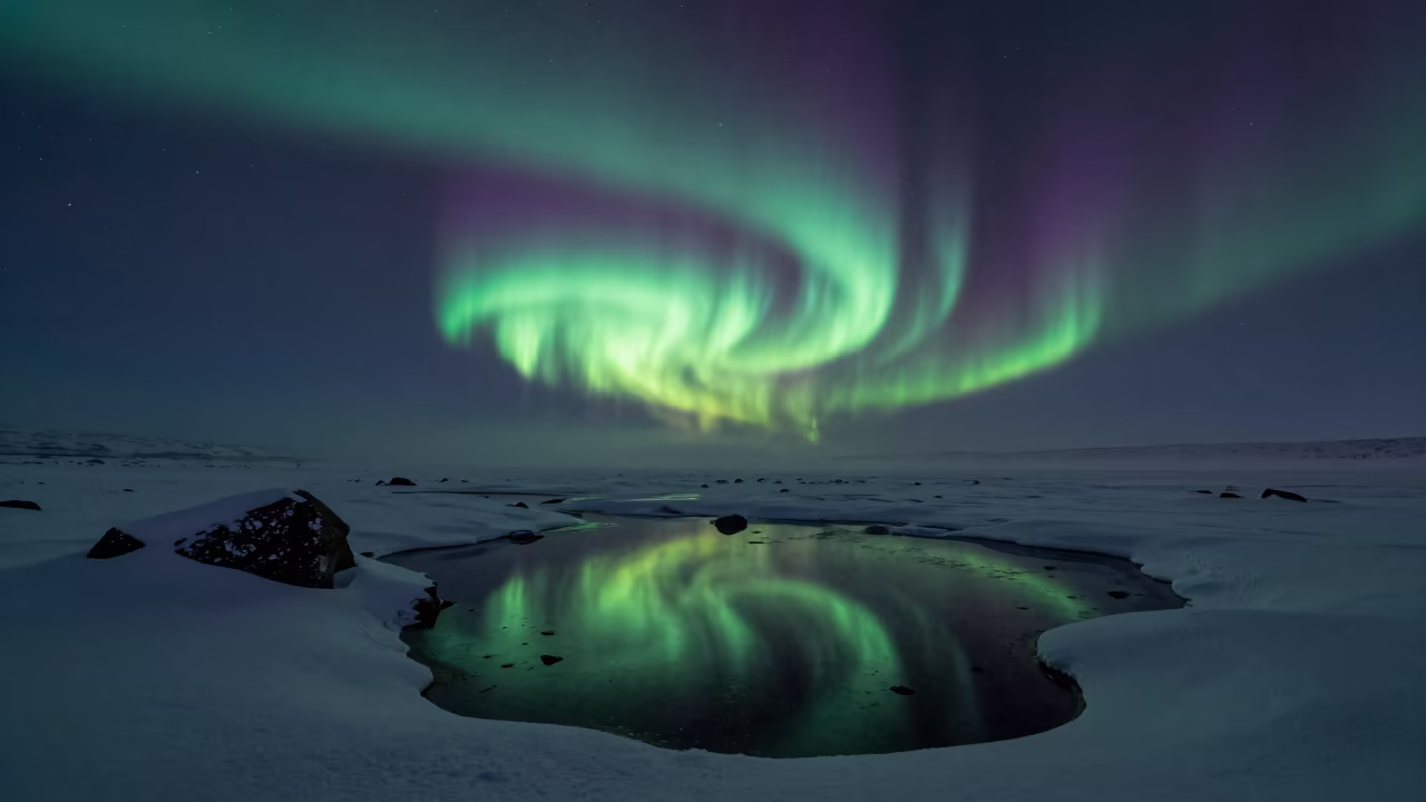 Aurora Borealis Reflected in Winter Meltwater Pools in beneath a hard winter sky over snowfields in Yukon