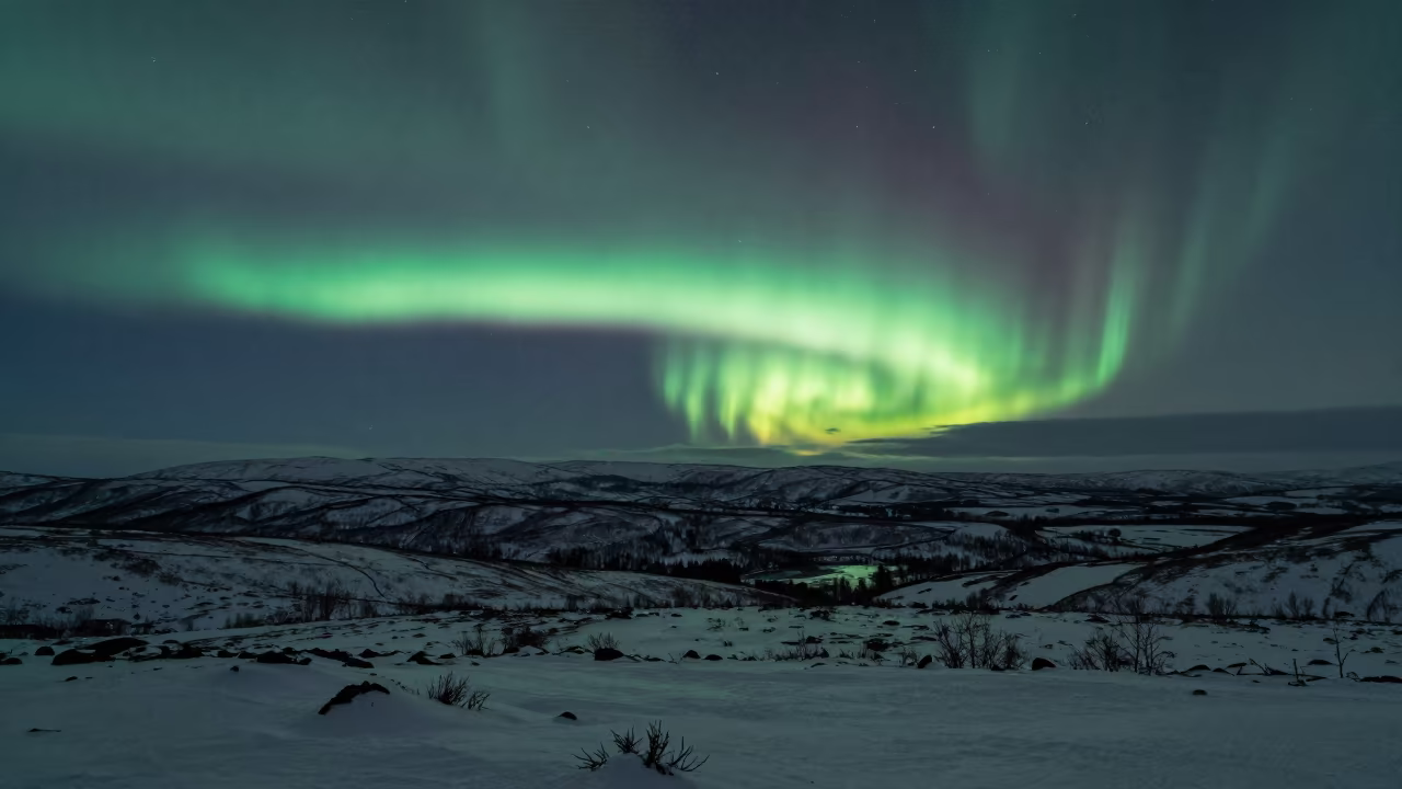Aurora Over Norwegian Tundra Ridge at Midnight in from a ridge above layered foothills in Norway
