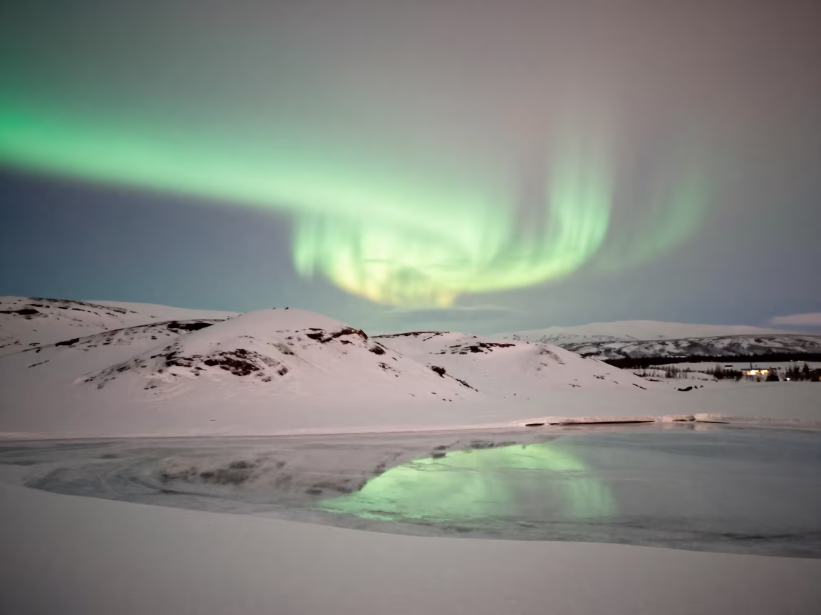 Aurora Over Snowy Lapland Valley Ridge in from a ridge above layered foothills in Lapland