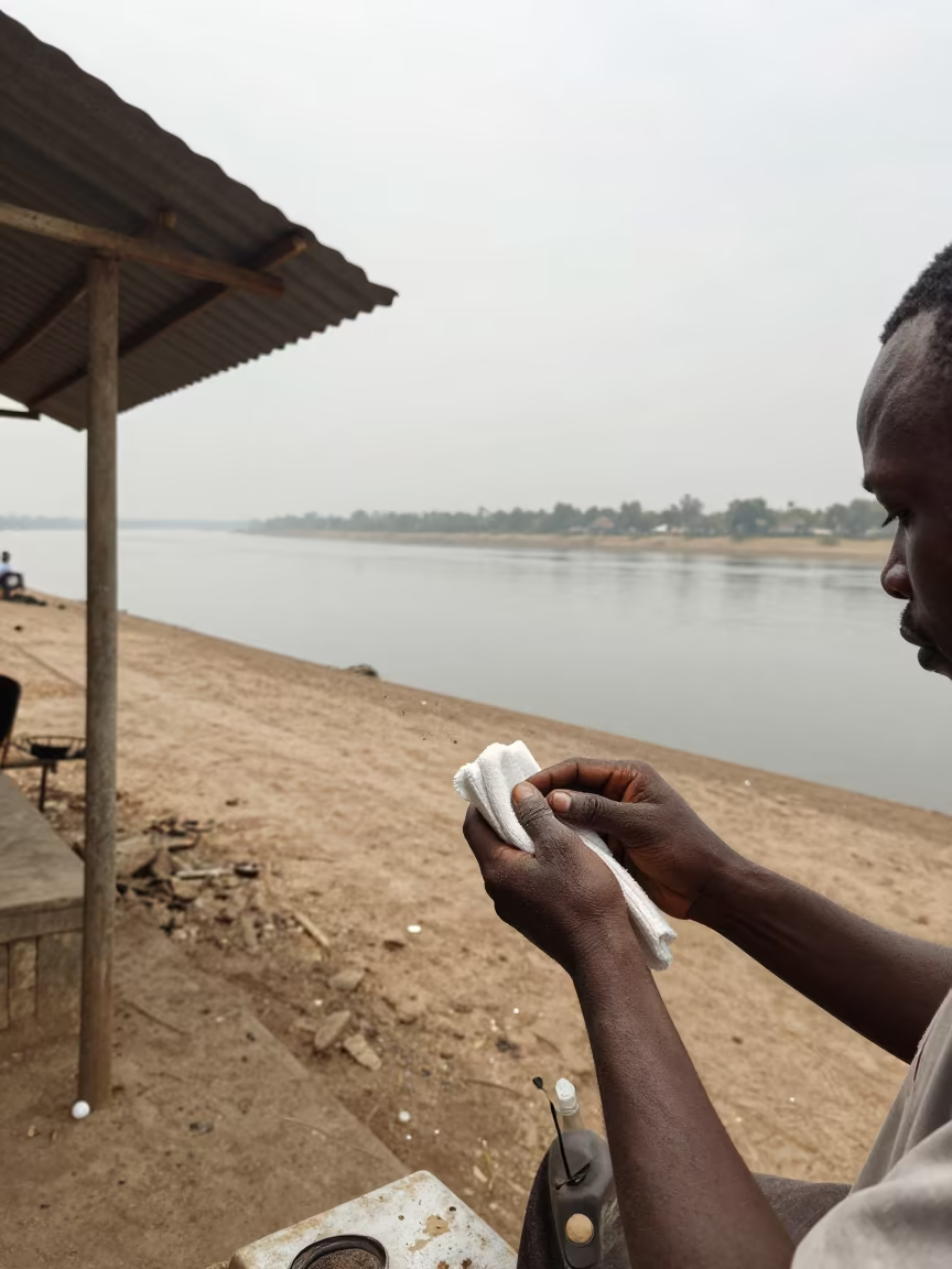 Barber Wiping Hands Riverside Shed Noon in near Iseyin