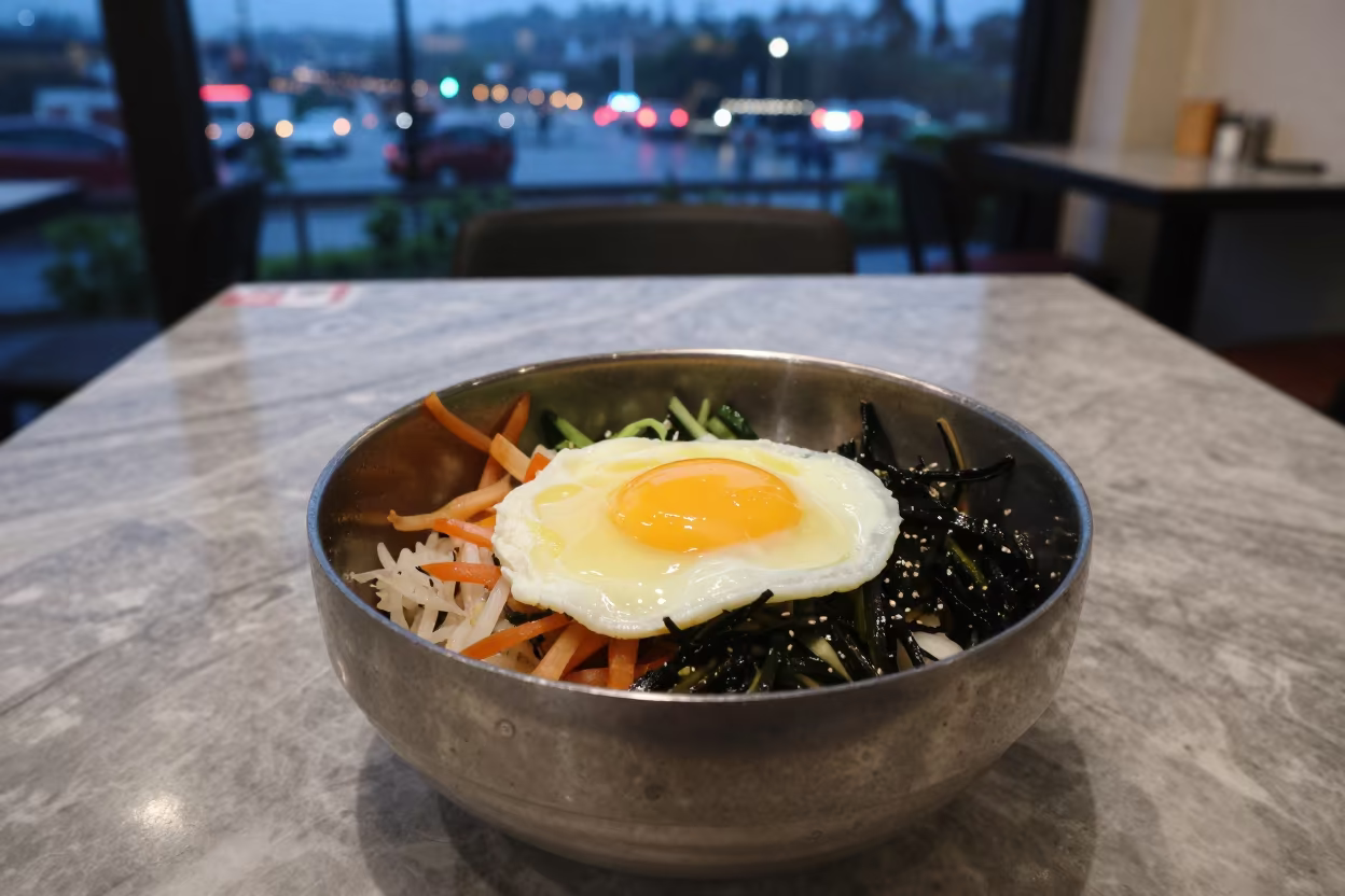 Bibimbap Bowl with Raw Egg on Marble Table in on a marble cafe table in Alleppey