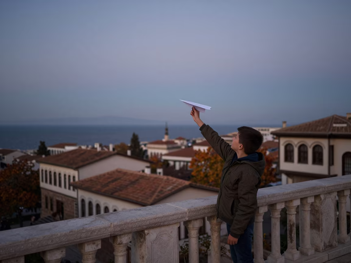 Boy Launching Paper Plane at Twilight Balcony in in Afyonkarahisar