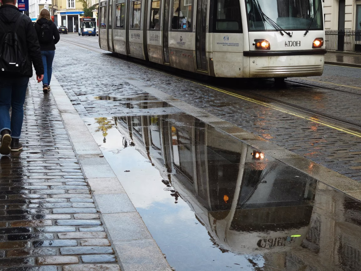 Bristol Street Scene with Tram Reflection on Wet Cobblestones at Noon in in Bristol, United Kingdom