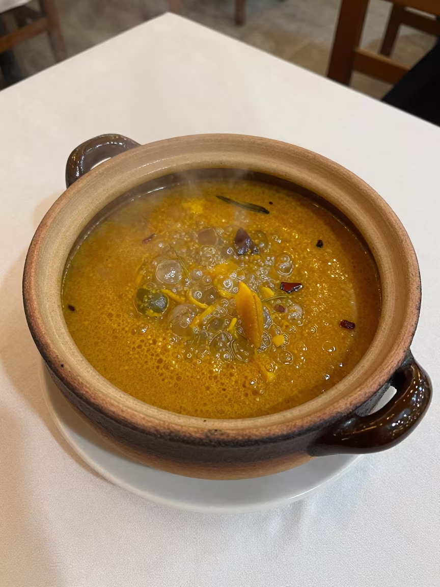 Bubbling Curry Pot on Linen Table in Heraklion in on a linen-covered restaurant table in Heraklion