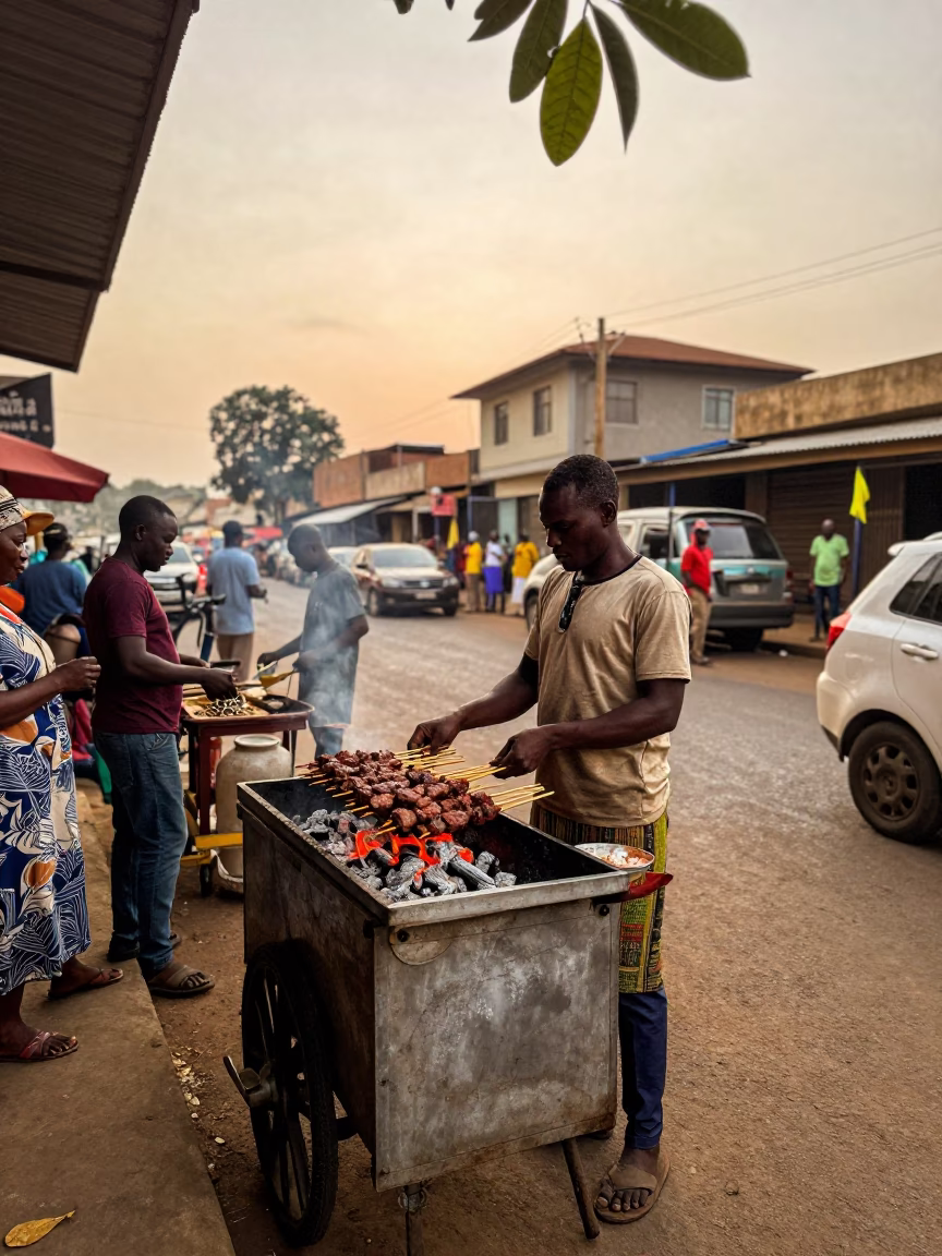 Busy Accra Ghana Street Scene with Suya Vendor and Leaf Shadows in Evening Light in in Accra, Ghana