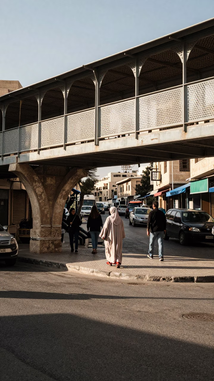 Busy Amman Street Corner with Perforated Metal Overpass and Pedestrians in Early Afternoon Light in in Amman, Jordan