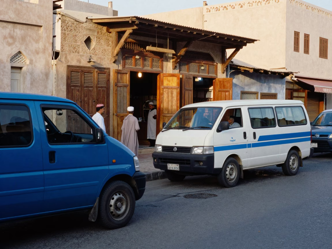 Busy Muscat Street Scene with Blue Minivan and Local Shopkeeper in Early Afternoon Light in in Muscat, Oman