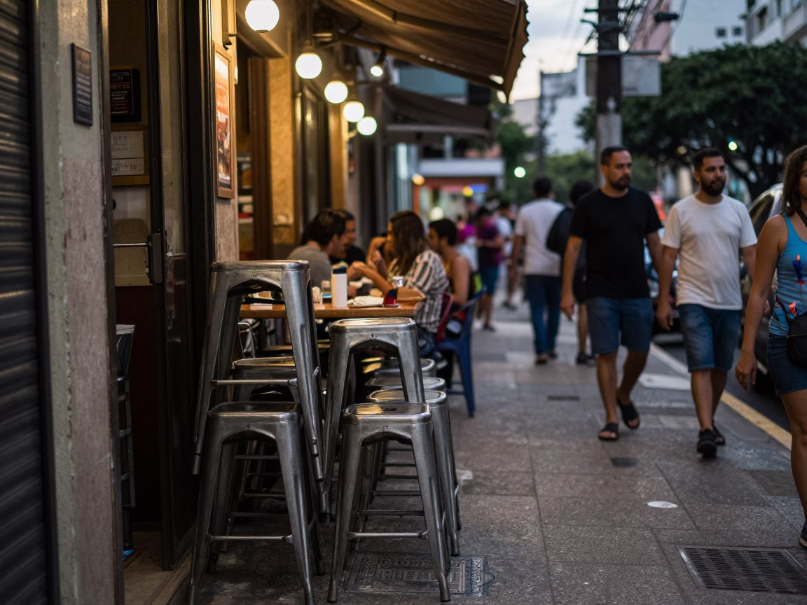 Busy São Paulo street scene at dusk with metal stools and ashtray in in São Paulo, Brazil