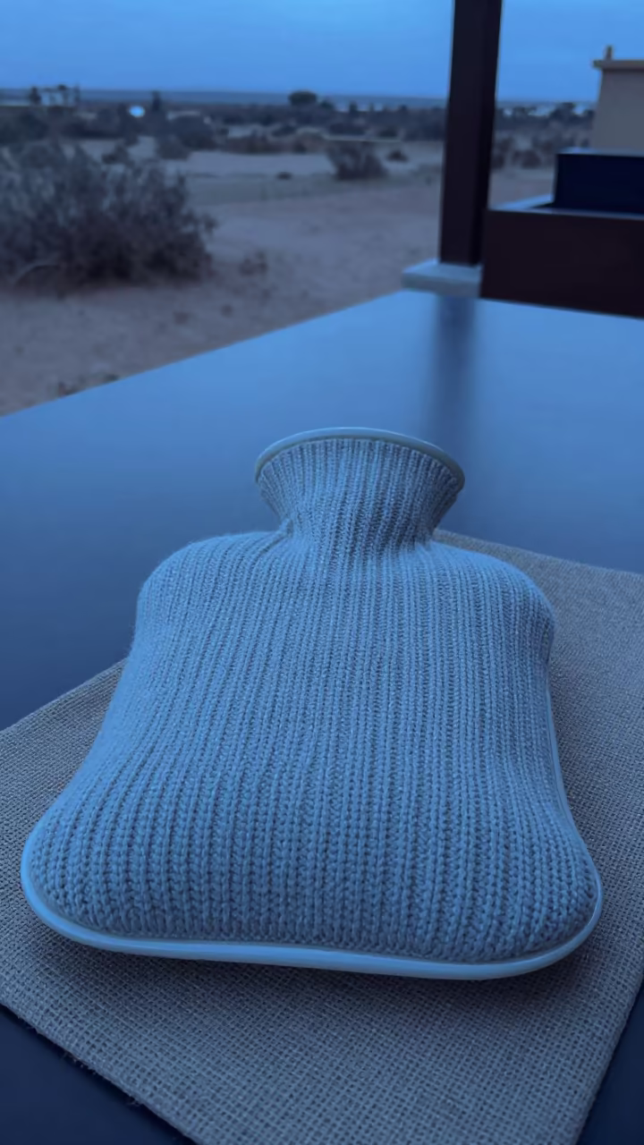 Ceramic Hot Water Bottle Knitted Cover Asmara in on a reading nook cushion in Asmara