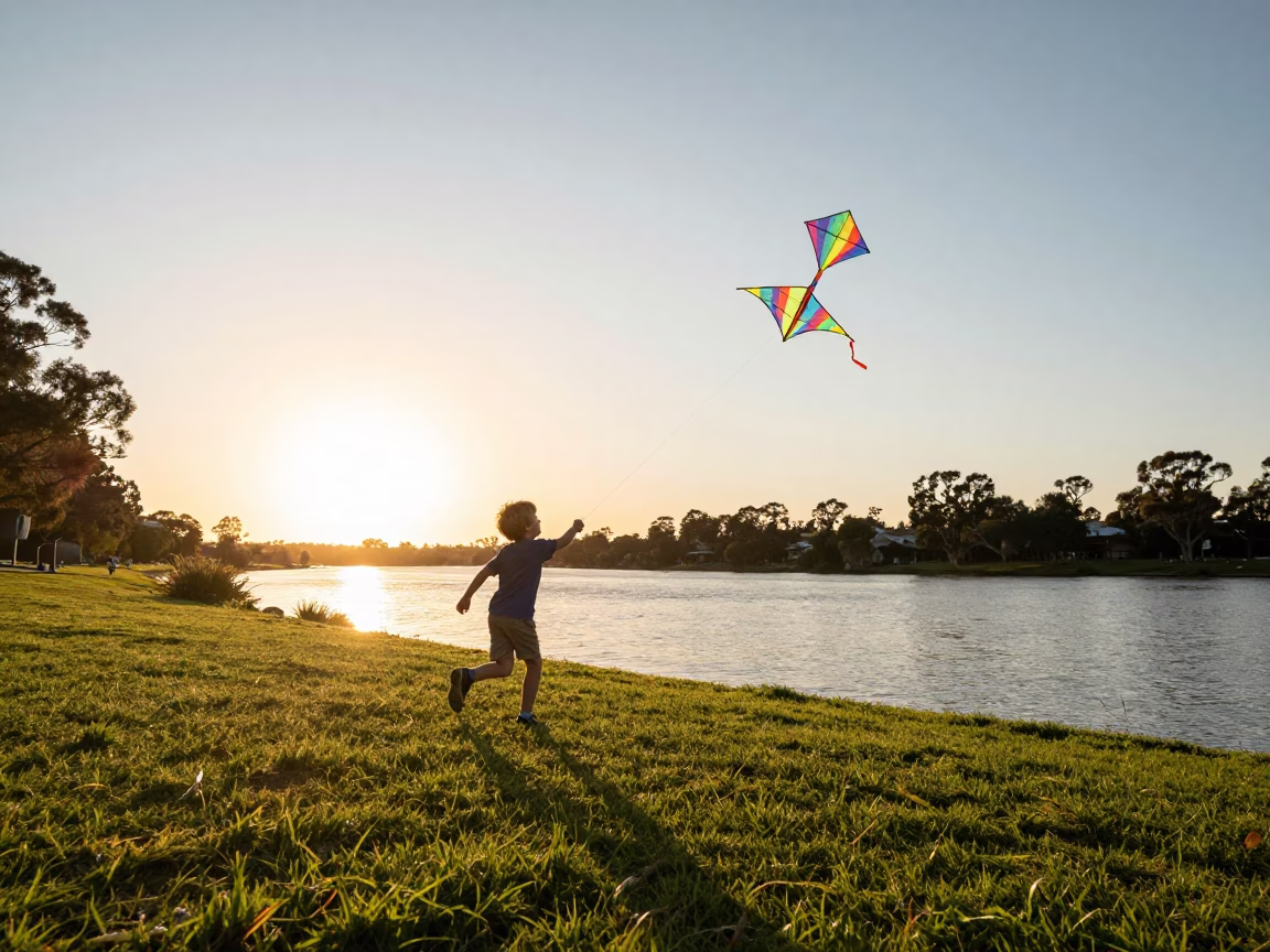 Child Flying Colorful Kite Near Adelaide Riverbank at Golden Hour Sunset in in Adelaide, South Australia, Australia