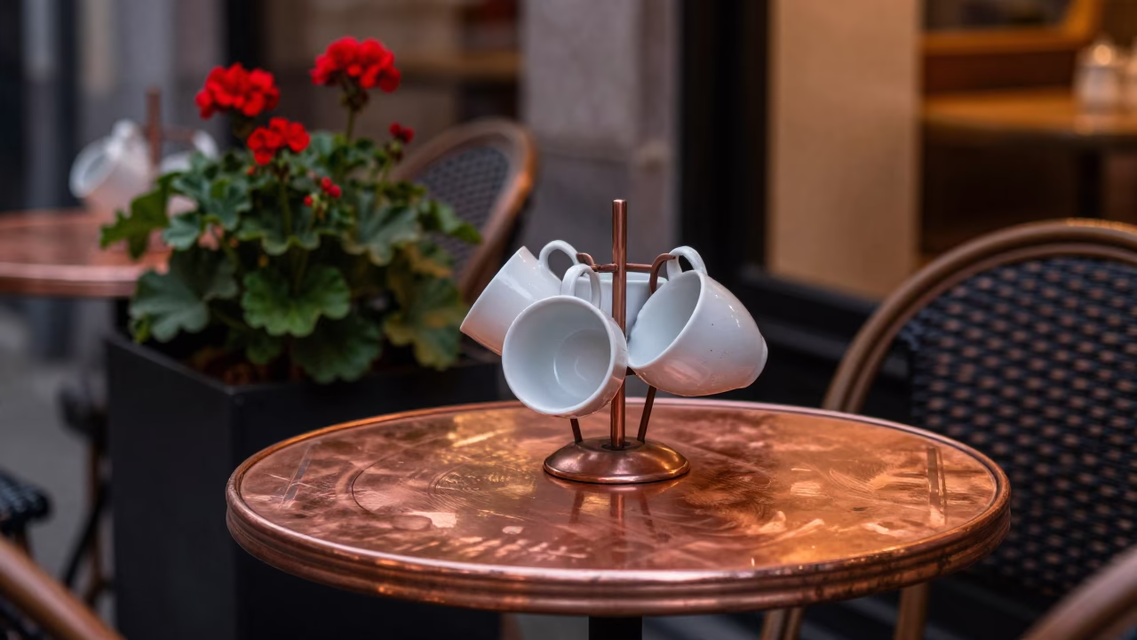 Copper dusk light on Brussels cafe table with geraniums and ceramic mugs in in Brussels, Belgium