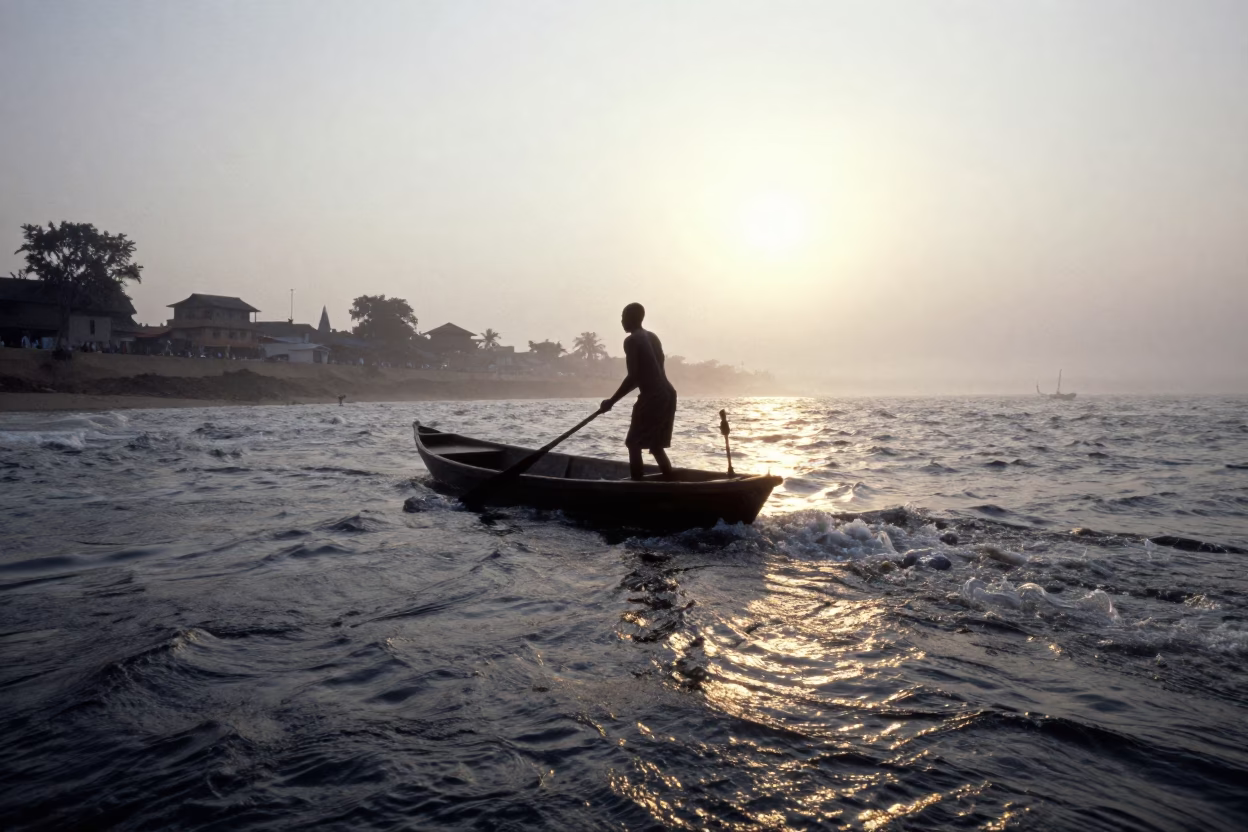 Silhouette of Coracle Fisherman Paddling Rapids in beside a fogbound harbor mouth near Bamako