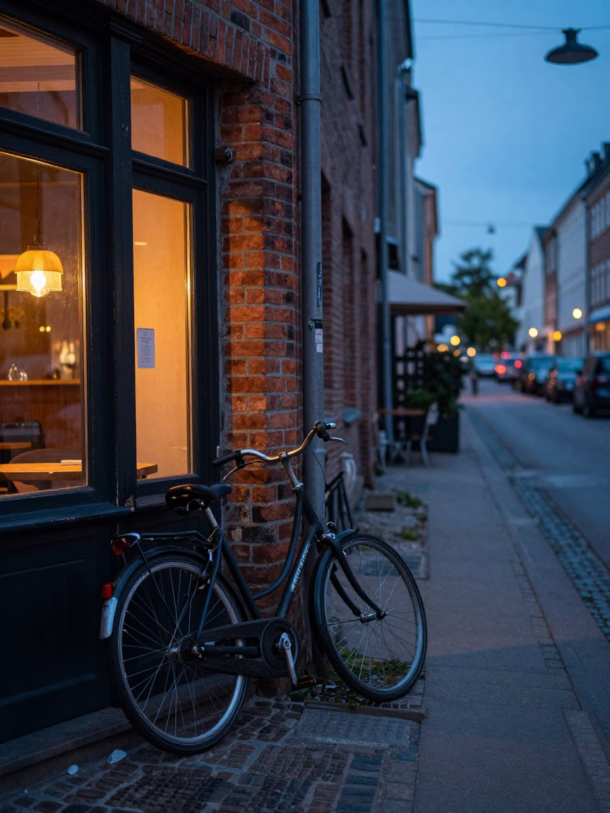 Dawn light on Copenhagen street with bicycle leaning against brick cafe facade in in Copenhagen, Denmark