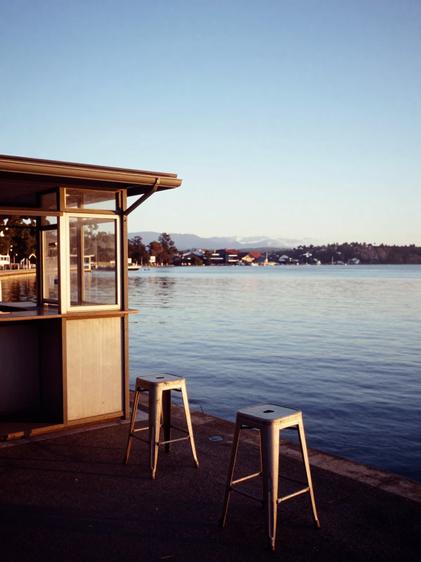 Dawn light on Hobart waterfront with metal stools and ferry leaving harbor in in Hobart, Tasmania, Australia