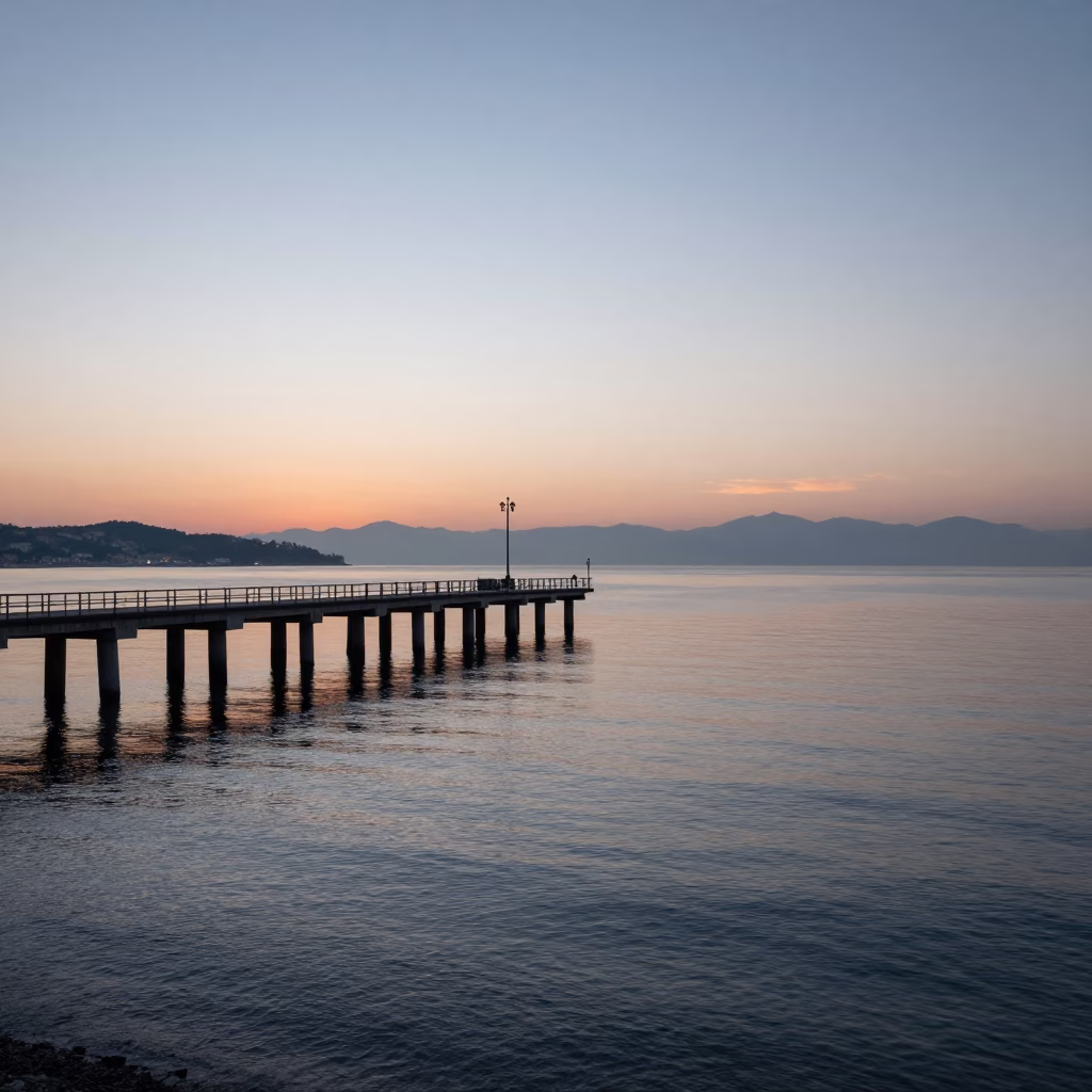 Dawn light on Naples Bay pier and calm water reflections before sunrise in in Naples, Italy