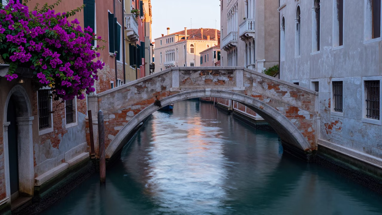 Dawn light on Venetian canal with bougainvillea and historic architecture in in Venice, Italy