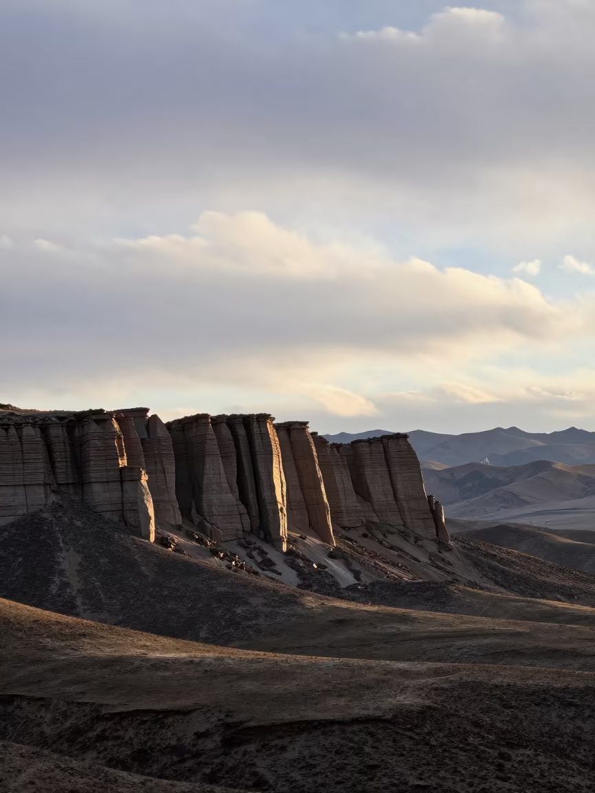 Dolerite Columns at Dawn Over Tibetan Foothills in from a ridge above layered foothills in Tibet