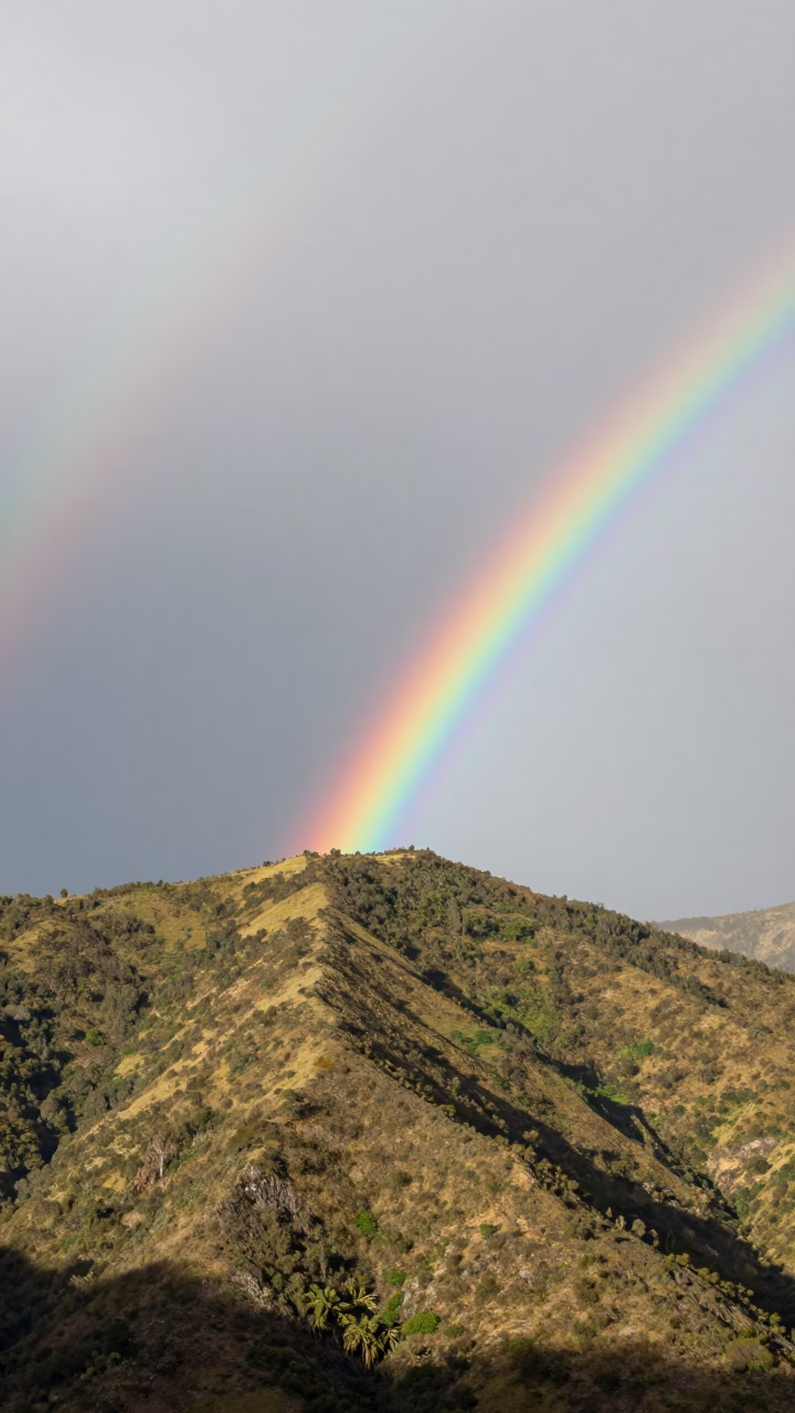 Double Rainbow Over Peruvian Mountain Ridge in beneath fast-moving cloud bands in Peru