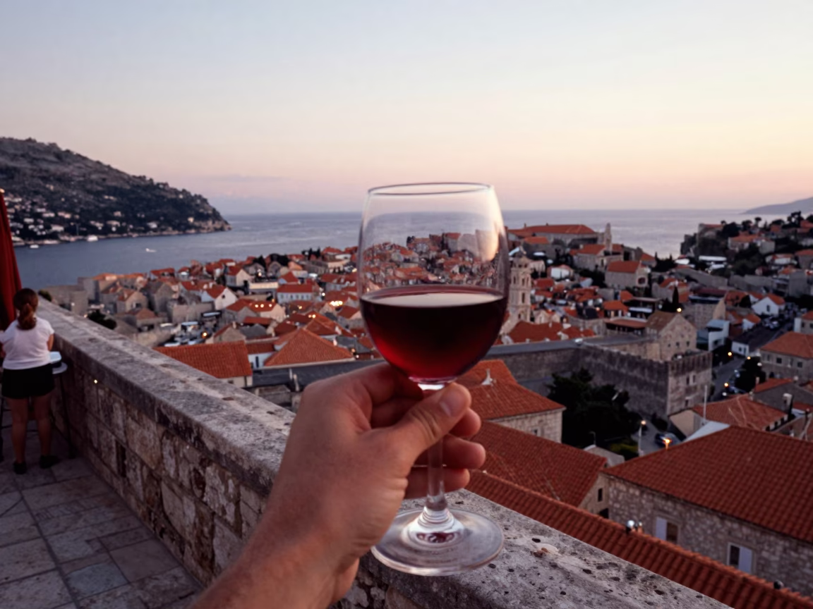 Dubrovnik Evening Terrace View with Red Wine and Adriatic Sailboat at Dusk in in Dubrovnik, Croatia