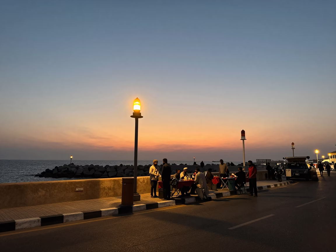 Dusk street scene in Muscat Oman with coastal breakwater warning beacons and folding tables in in Muscat, Oman